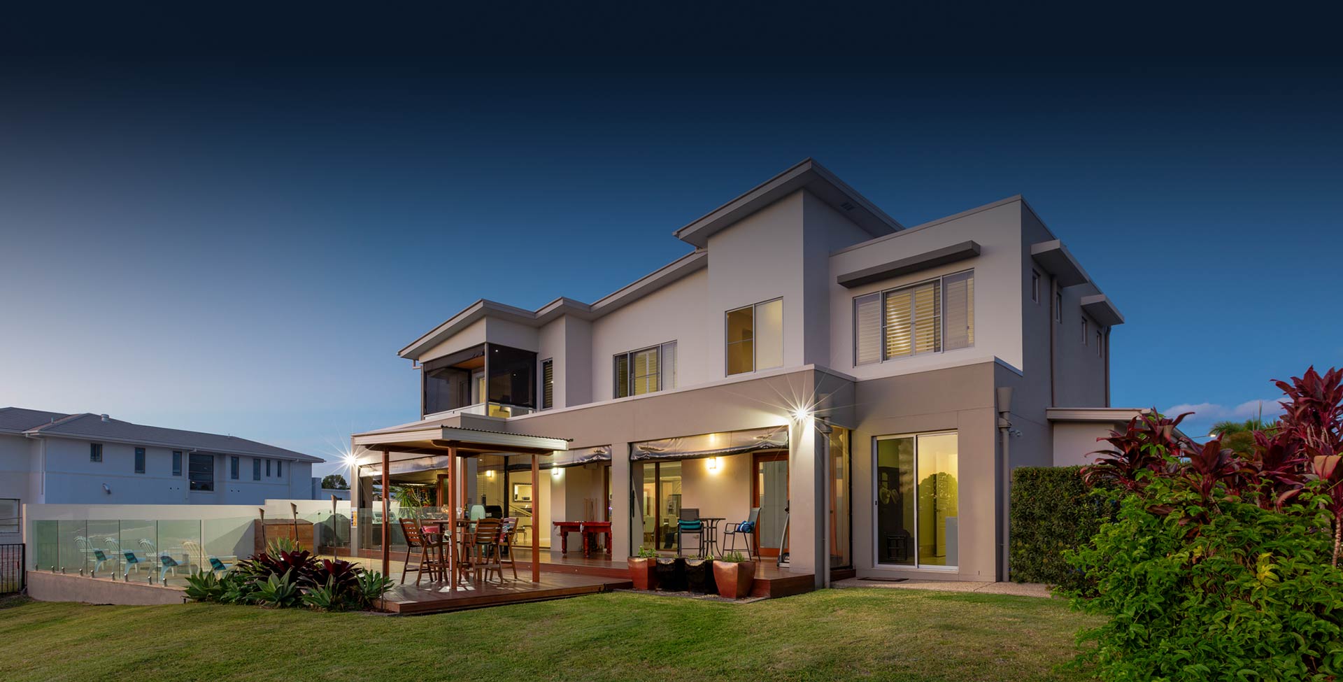 Modern multilevel house exterior with pool at dusk